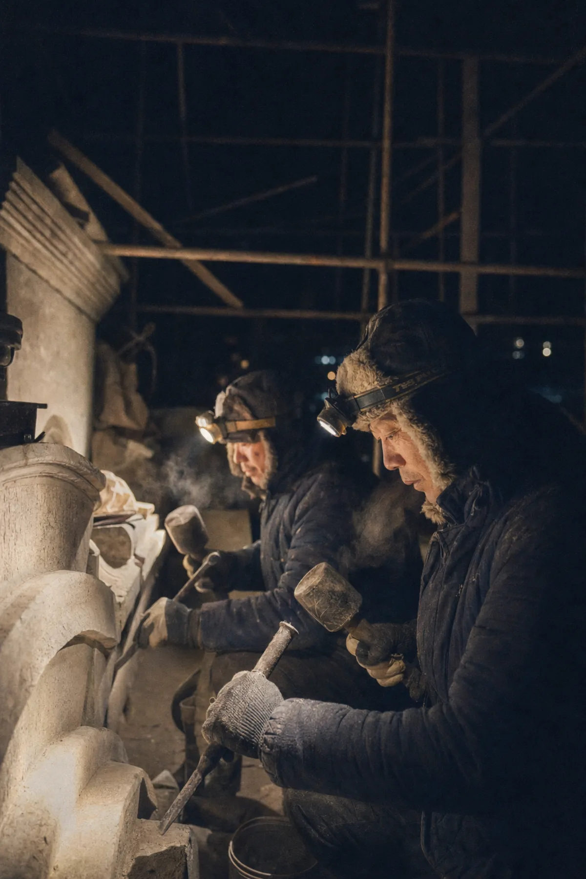 Two stonemasons working by headlamp in the half-built stone cellar