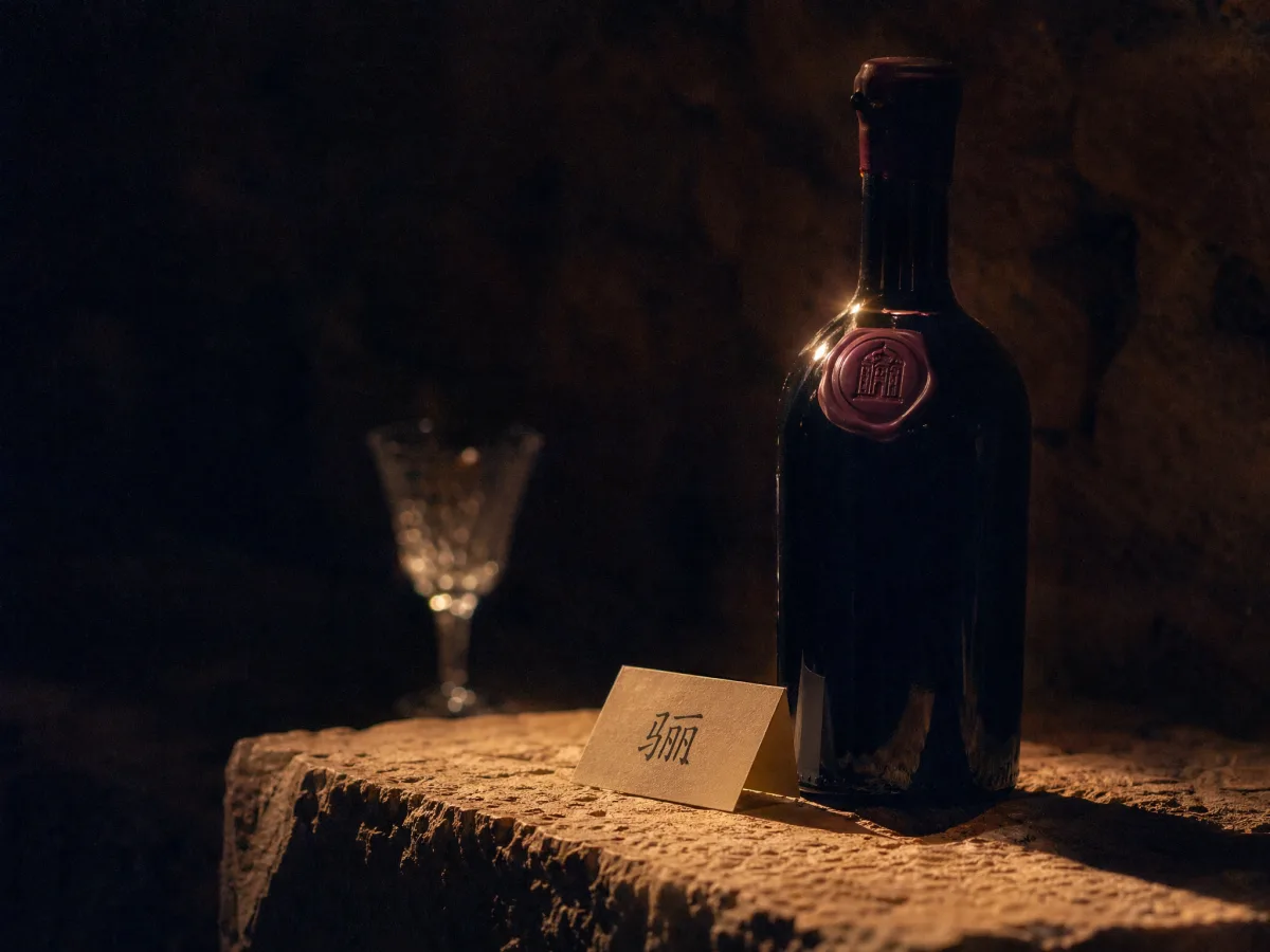 A single Lilu bottle on a stone plinth with a handwritten cellar tag beside it