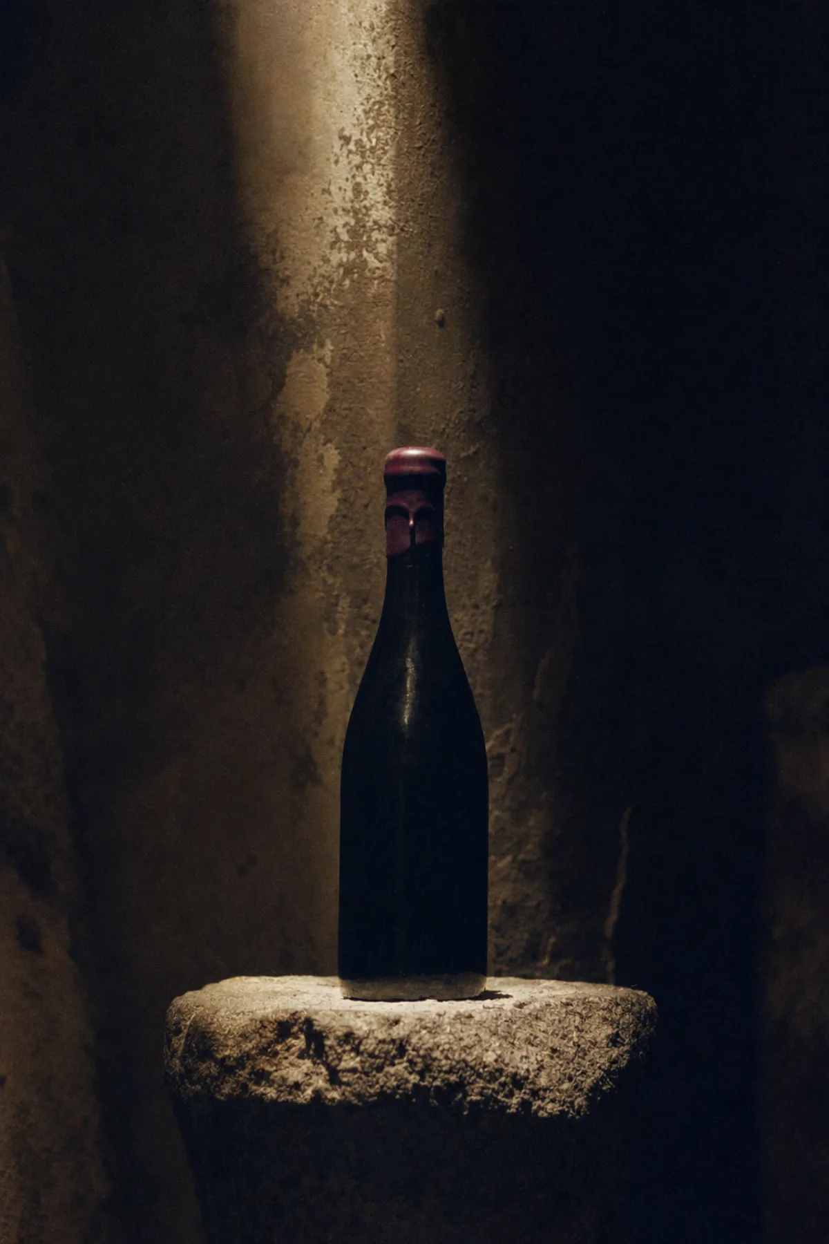 石窖石台上一瓶不贴标的深色酒，封蜡呈深紫色