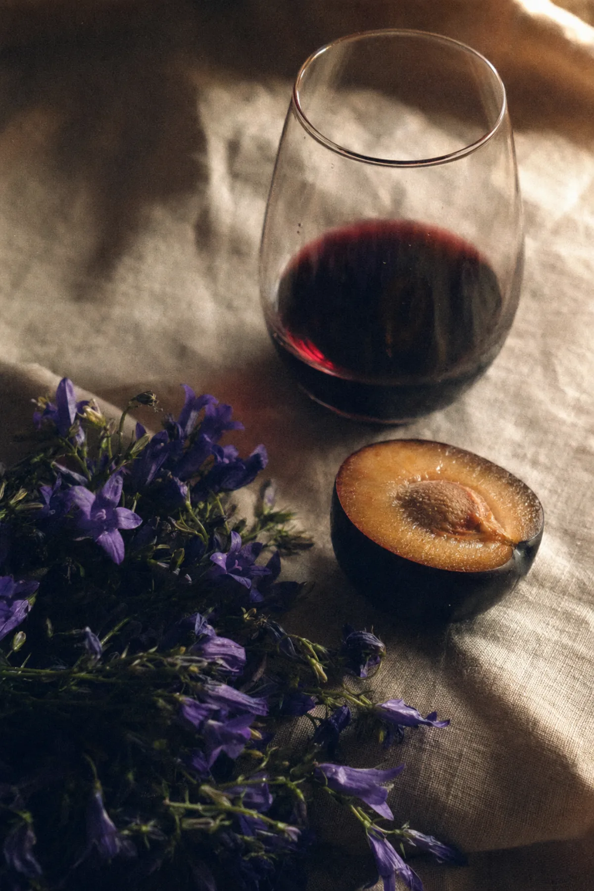 亚麻布上的紫罗兰、切开的黑李，以及一杯马瑟兰