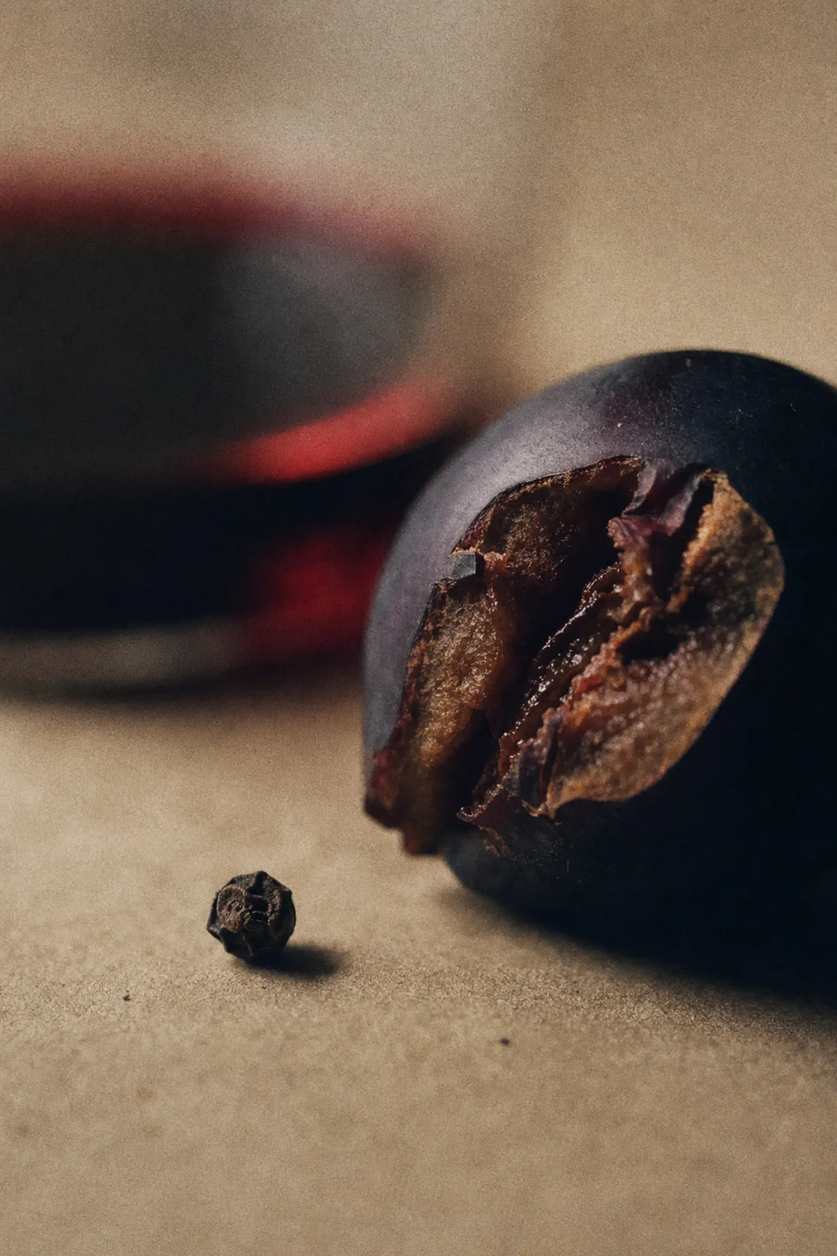 牛皮纸上的一颗黑胡椒与烟熏李旁，一杯虚焦的西拉